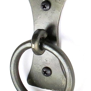 May include: A black metal ring pull handle with a decorative backplate. The handle is attached to the backplate with two screws.