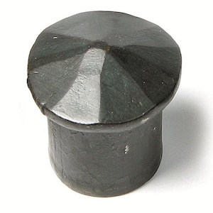 May include: A black metal bottle stopper with a pointed top and a cylindrical base. The top has a geometric design with a white center.