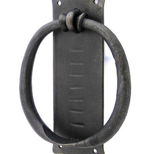 May include: A black metal door knocker with a circular ring and a rectangular backplate. The ring is attached to the backplate with a decorative knot.