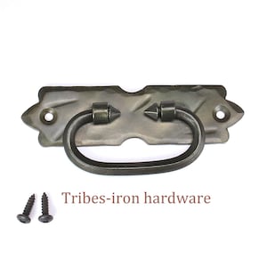 May include: A dark grey metal drawer pull with a curved handle and decorative details. The pull has a textured surface and includes two screws. The text "Tribes-iron hardware" is displayed below the pull.