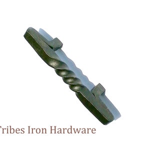 Peut inclure: Une poignée de porte en métal torsadé avec une finition gris foncé. La poignée a une forme carrée à chaque extrémité. Tribes Iron Hardware est imprimé sous la poignée.