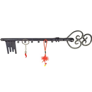 Könnte beinhalten: Schwarzer Schlüssel-förmiger Wandhaken aus Metall mit mehreren Haken zum Aufhängen von Schlüsseln, Schmuck oder anderen kleinen Gegenständen. Der Haken ist am Ende mit einem geschwungenen Design verziert. An den Haken hängen rote und schwarze Quasten.