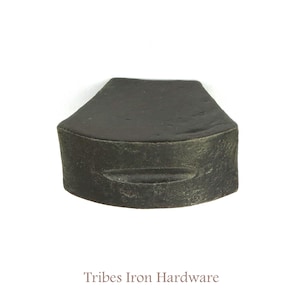 Può includere: Un pomello per armadio in metallo grigio scuro con una forma rettangolare leggermente arrotondata e una scanalatura sottile al centro. Tribes Iron Hardware è stampato sotto il pomello.