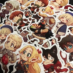 May include: A collection of die-cut vinyl stickers featuring various anime-style characters in chibi proportions. The designs include a horned dwarf holding a bowl of food, a blonde elf, a knight with a mushroom, and other fantasy-themed figures.