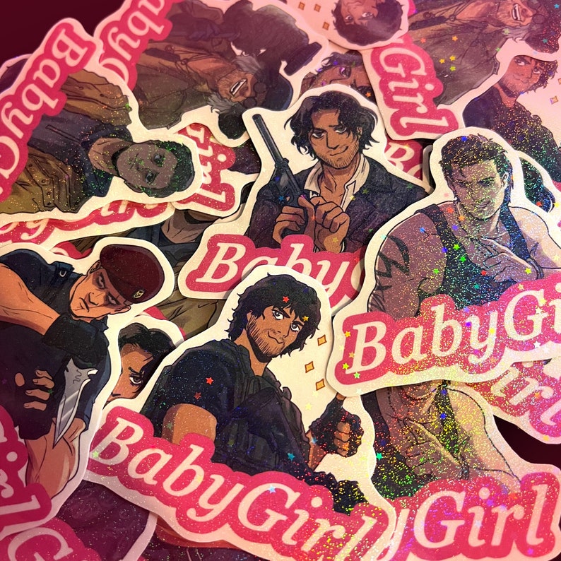 May include: A selection of glittery stickers with illustrations of characters. The stickers feature pink and white text that reads "Baby Girl". The illustrations depict people with weapons and serious expressions.