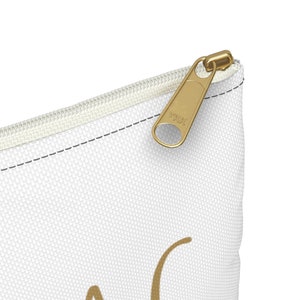 May include: White canvas zippered pouch with a gold zipper pull. The zipper pull has the text "YKK" on it.