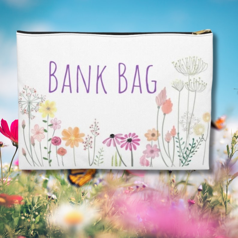 May include: White zippered pouch with the text "BANK BAG" in purple lettering. The pouch is decorated with a watercolour floral design of pink, yellow, and green flowers.