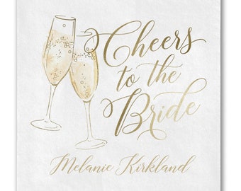 May include: Gold foil calligraphy on a white background with two champagne flutes and the text "Cheers to the Bride Melanie Kirkland".
