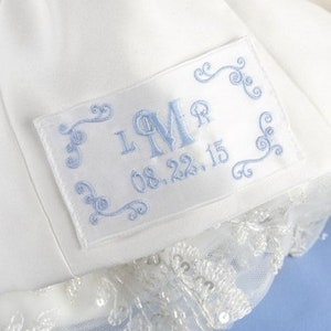 May include: White satin fabric with a blue embroidered label. The label has a monogram "LMR" and the date "08.22.15".