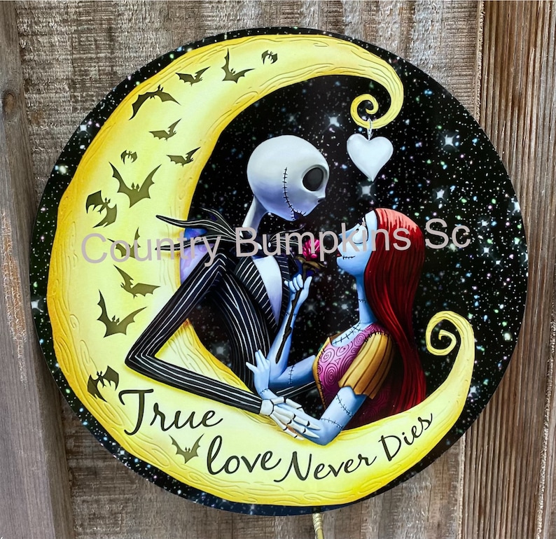 May include: A round metal sign featuring a yellow crescent moon against a black starry night sky.  The characters Jack Skellington and Sally from the film The Nightmare Before Christmas are shown in a romantic embrace.  The text "True Love Never Dies" is written in a stylised font on the moon.