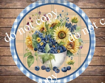 May include: A round, blue and white checkered plate with a white bowl filled with blueberries, grapes, and sunflowers. The plate has a brown wooden background.