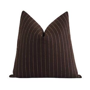 May include: A decorative throw pillow with a dark brown background and vertical pinstripes in a lighter brown color. The pillow has a soft, textured appearance and a classic design, suitable for home decor.
