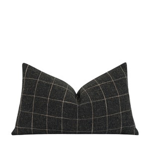 May include: A black and white plaid pillow with a subtle sheen. The pillow is rectangular and has a slightly pointed shape at the top.