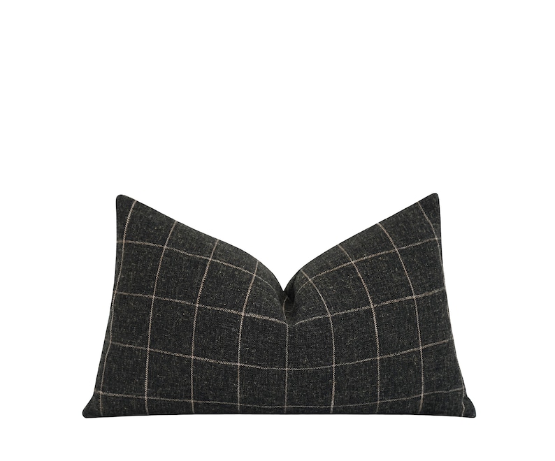 May include: A black and white plaid pillow with a subtle sheen. The pillow is rectangular and has a slightly pointed shape at the top.