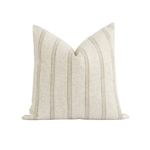 May include: A beige throw pillow with brown and blue stripes. The pillow is made of a soft, textured fabric.