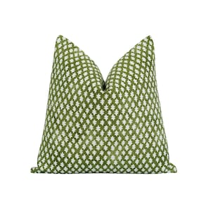 Op de afbeelding: Een decoratief vierkant kussen met een groene achtergrond en een wit geometrisch patroon. Het kussen heeft een zacht, getextureerd uiterlijk en is bedoeld voor woondecoratie.