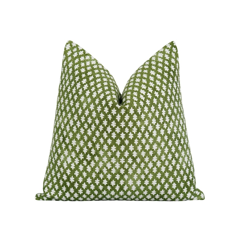 Op de afbeelding: Een decoratief vierkant kussen met een groene achtergrond en een wit geometrisch patroon. Het kussen heeft een zacht, getextureerd uiterlijk en is bedoeld voor woondecoratie.