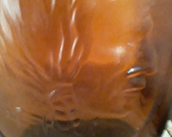 May include: A close-up of a brown glass bottle with a rounded base. The bottle has a dark amber color and a smooth, reflective surface. The light reflects off the surface, creating highlights and shadows.