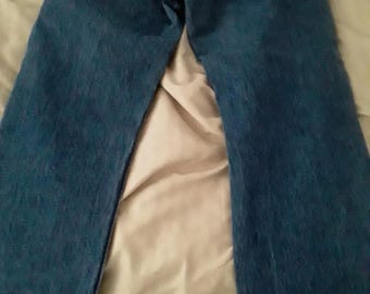 May include: A pair of blue denim jeans featuring two back pockets with stitched detailing and a tan leather patch located on the back waistband. The jeans have a classic straight-leg cut and a medium blue wash with visible fabric texture throughout.