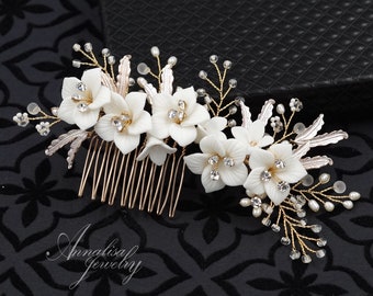 May include: A white floral hair comb with gold wire and pearl accents. The comb has a delicate design with small white flowers and rhinestones.