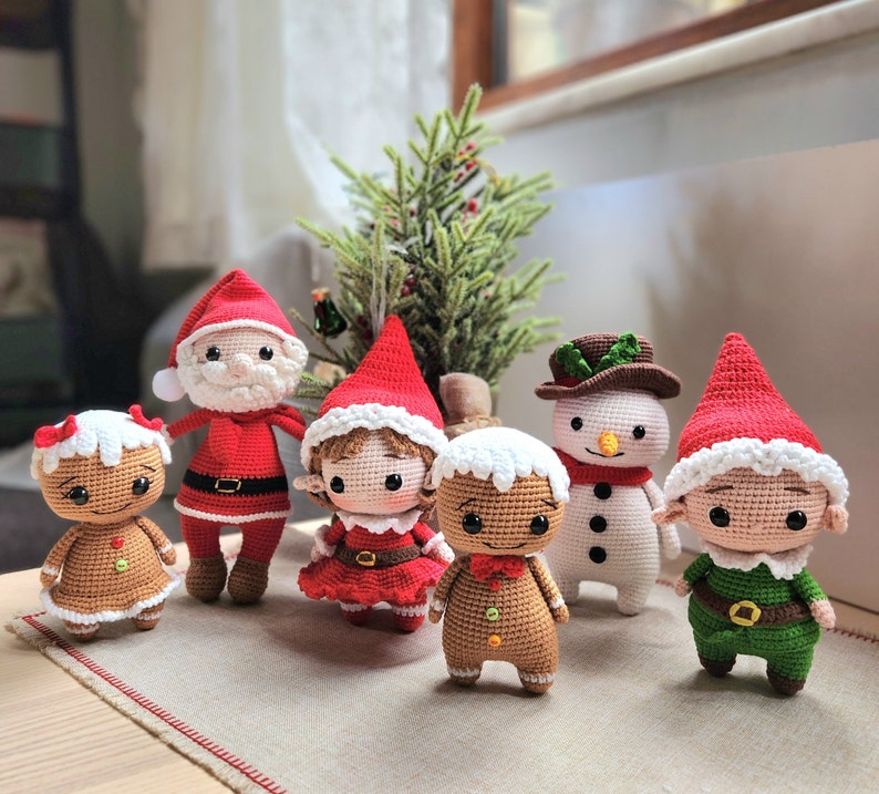 May include: A group of seven crocheted Christmas decorations, including a gingerbread person, a snowman, a Father Christmas, and three elves. The decorations are all handmade and feature intricate details.
