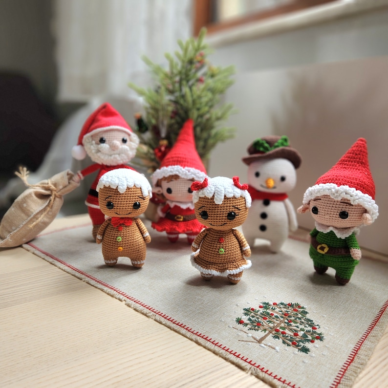 May include: A collection of crocheted Christmas decorations, featuring Santa Claus, a gingerbread person, a snowman, an elf, and a Christmas tree. The decorations are all handmade and have a charming, festive appearance.