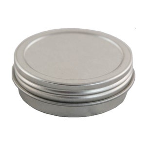 May include: A silver metal tin with a round lid. The tin is closed and the lid is on top of the tin.
