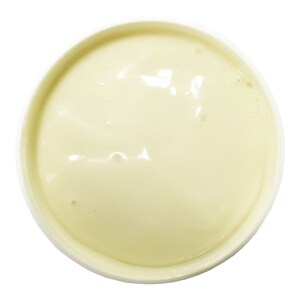 May include: Overhead view of a white bowl filled with a smooth, pale yellow substance. The substance has a glossy appearance with subtle variations in color and texture, suggesting a creamy consistency. The bowl is set against a clean white background.