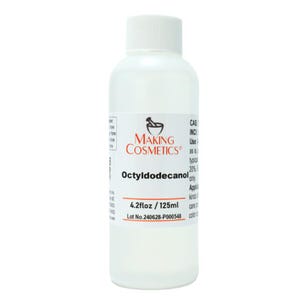 Op de afbeelding: Een heldere fles met een witte dop, met het label "MAKING COSMETICS". Het etiket toont de productnaam "Octyldodecanol" en het volume van 125 ml. De fles staat tegen een witte achtergrond.