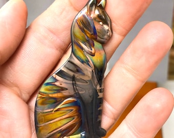 May include: A iridescent cat figurine with a black, gold, and blue color scheme. The figurine is made of metal and has a sleek, modern design.