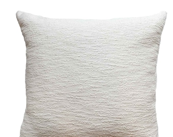 May include: A white square pillow with a textured fabric. The pillow is made of a soft, woven material.