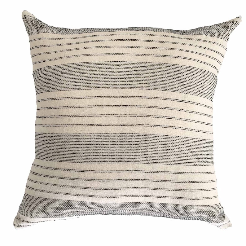 May include: A white throw pillow with black stripes. The pillow is made of a soft, textured fabric.