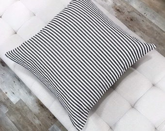 Könnte beinhalten: Ein quadratisches Kissen mit schwarzen und weißen Streifen. Das Kissen ist aus weichem, gewebtem Stoff.