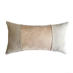 May include: A long rectangular pillow with a beige suede center panel and two linen side panels. The pillow is a light beige color.