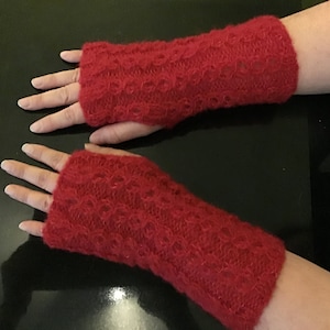 Peut inclure: Une paire de mitaines en tricot rouge avec un motif ajouré.