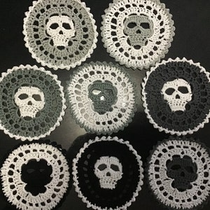 May include: Eight crocheted doilies with a skull design in shades of gray and white.