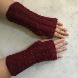 Peut inclure: Une paire de mitaines bordeaux. Les gants sont faits d'une matière tricotée texturée. La partie du poignet est plus longue que la partie de la main. Les gants sont conçus pour garder les mains au chaud tout en laissant les doigts libres.
