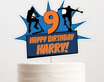 May include: A blue and orange birthday cake topper with a comic book style design. It features a number 9, two figures on skateboards, and the text "Happy Birthday Harry!"