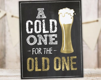 Può includere: Un cartello nero in ardesia con scritta in gesso bianco che recita "A Cold One - For The - Old One". A destra del testo c'è un bicchiere di birra dorato con una testa di schiuma bianca. Il cartello è disponibile in tre dimensioni: 40,6 x 50,8 cm, 27,9 x 35,6 cm e 20,3 x 25,4 cm.
