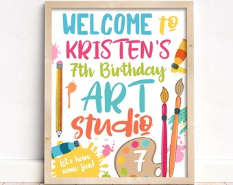 Può includere: Un cartello di benvenuto colorato per una festa di compleanno di 7 anni con il testo "Benvenuti allo studio d'arte di Kristen per il suo 7° compleanno" e la frase "Divertiamoci!" Il cartello presenta schizzi di vernice, pennelli, una tavolozza di colori e matite.