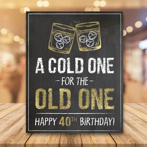 May include: A black chalkboard sign with gold lettering that reads "A cold one - for the - old one. Happy 40th Birthday!"  Two gold glasses with ice cubes clink together at the top of the sign.