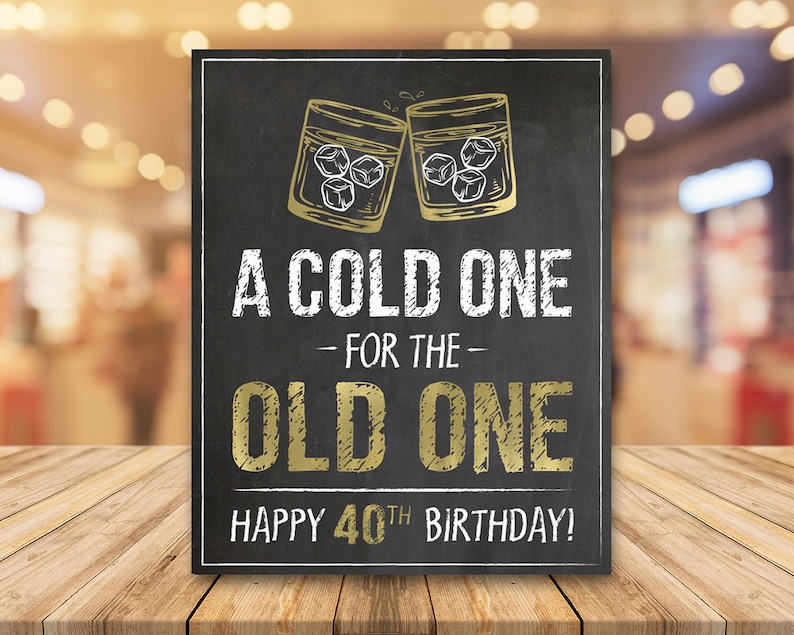May include: A black chalkboard sign with gold lettering that reads "A cold one - for the - old one. Happy 40th Birthday!"  Two gold glasses with ice cubes clink together at the top of the sign.