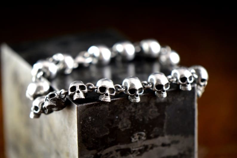 May include: A silver bracelet with a chain made of small skull charms.