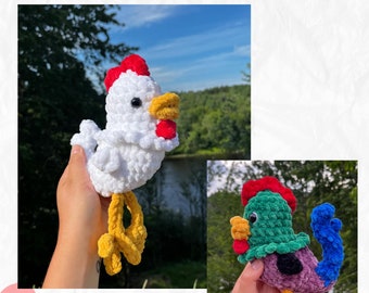 May include: Two crocheted rooster toys, one white with a red comb and yellow legs, and one green with a red comb and purple body with blue tail feathers and yellow legs. The toys are being held by hands against a blurred background of trees and sky.