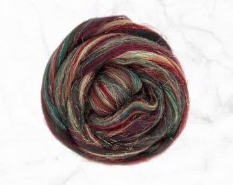 May include: A ball of red, green, and gold fiber with a sparkly finish. The fiber is arranged in a loose, swirling pattern.