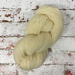 May include: A skein of pale yellow yarn, made from natural wool fibres. The yarn is soft and fluffy, and it is perfect for knitting or crocheting.
