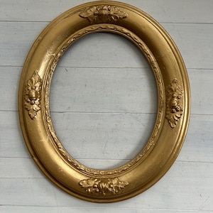 Peut inclure: Un cadre photo de forme ovale avec une finition en peinture dorée métallique. Le cadre présente un motif en relief décoratif avec des motifs floraux et de feuilles symétriques positionnés en haut, en bas et sur les côtés de la bordure.