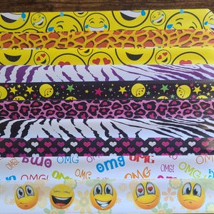 Könnte beinhalten: Ein Set aus zehn bunten Plastikarmbändern mit verschiedenen Mustern, darunter Zebrastreifen, Leopardenmuster und Smiley-Gesichter. Die Armbänder haben den Text "OMG" aufgedruckt.