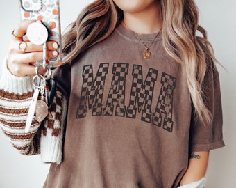 May include: Brown t-shirt with a checkered "MAMA" graphic. The shirt is oversized and has a relaxed fit.