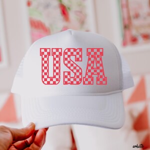 May include: White trucker hat with a red and white checkered "USA" graphic.